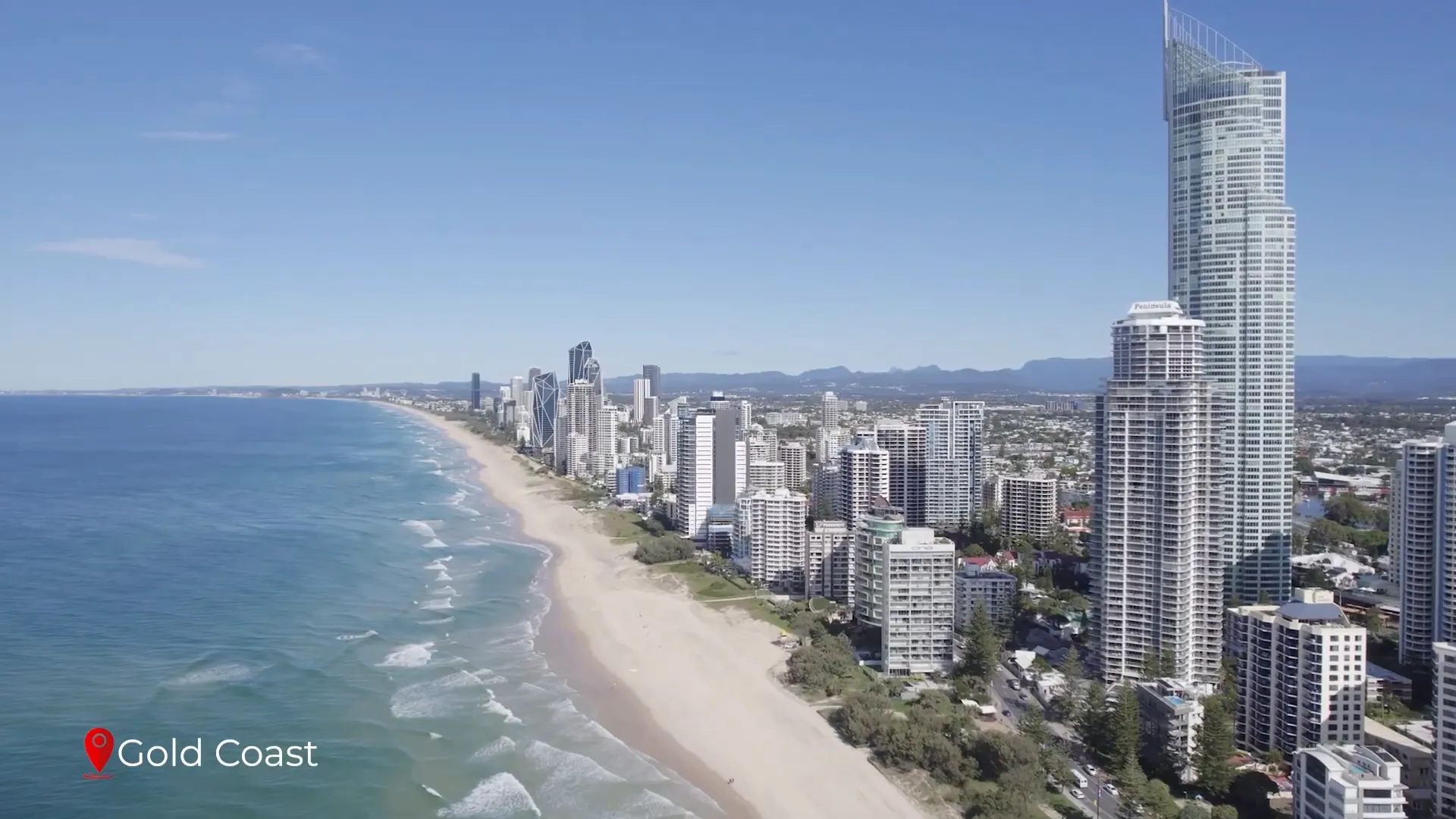Crowded golden sand beach at Surfers Paradise with surf and skyline