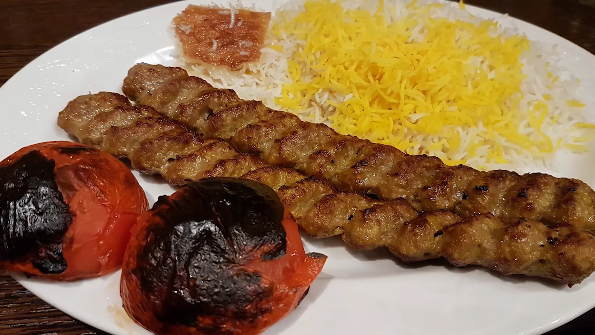 Close-up of saffron rice and chelo kebab on a decorative Persian plate