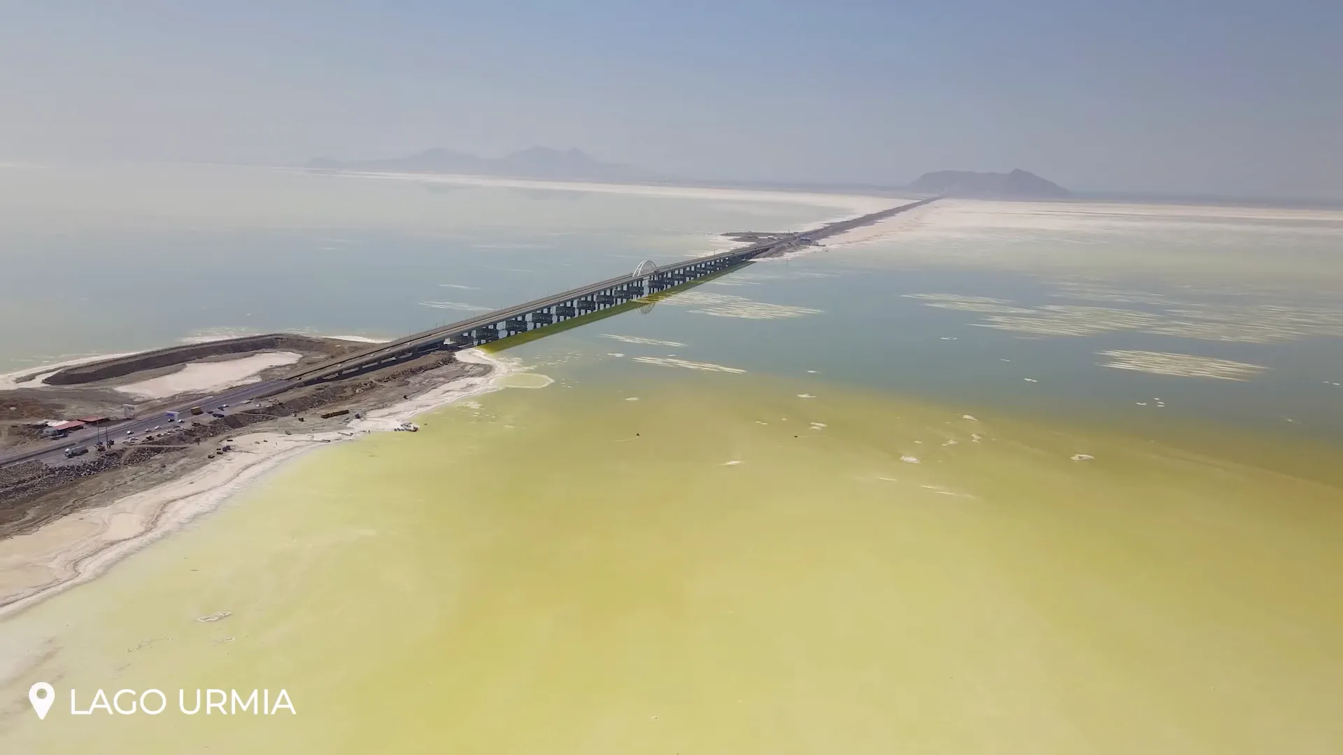 Wide view of Lake Urmia with reflective rosy surface and salt flats along the shore