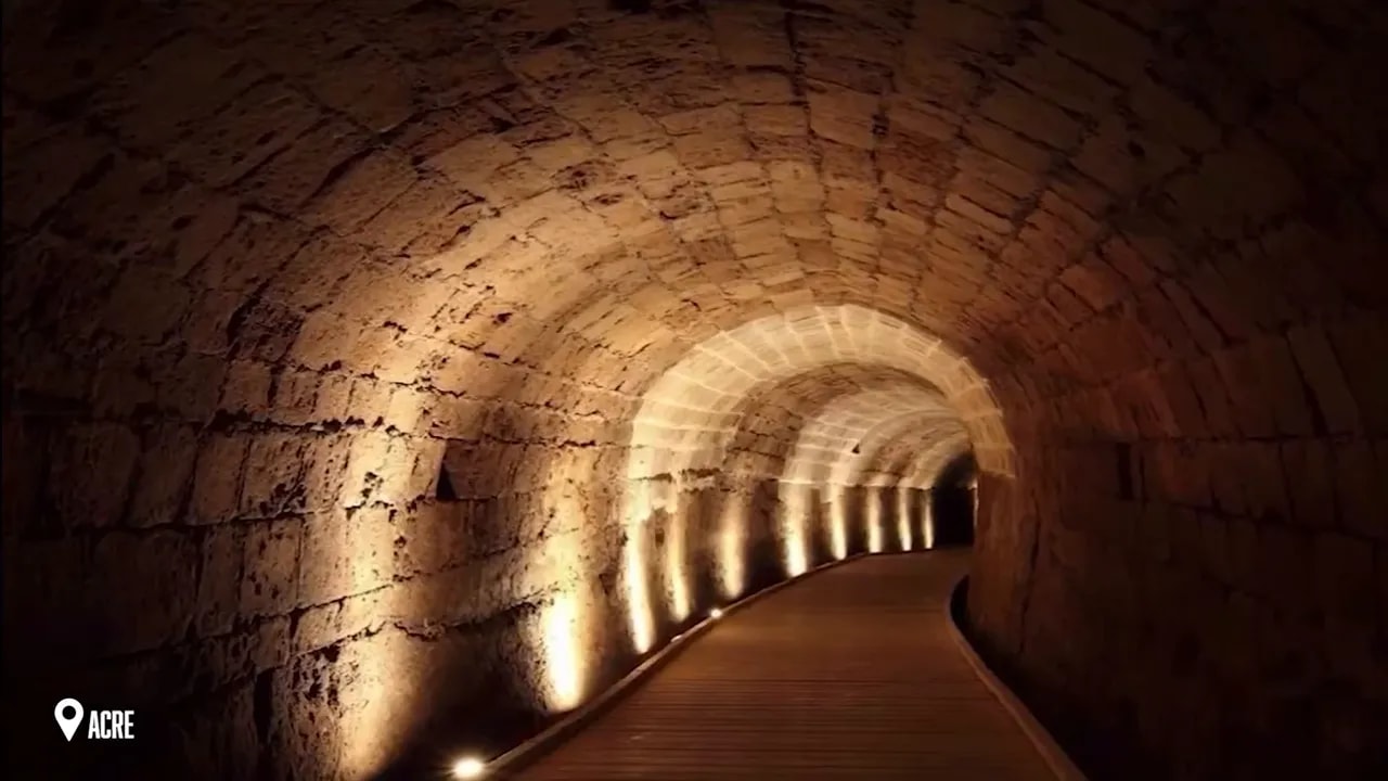 Illuminated stone tunnel with repeating arched ceiling in Acre