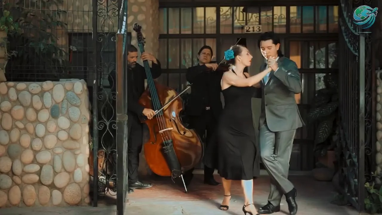 Tango dancers performing outside a building with musicians behind them
