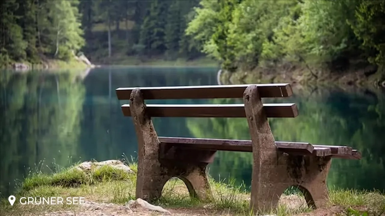 Wooden bench beside clear green water at Grüner See