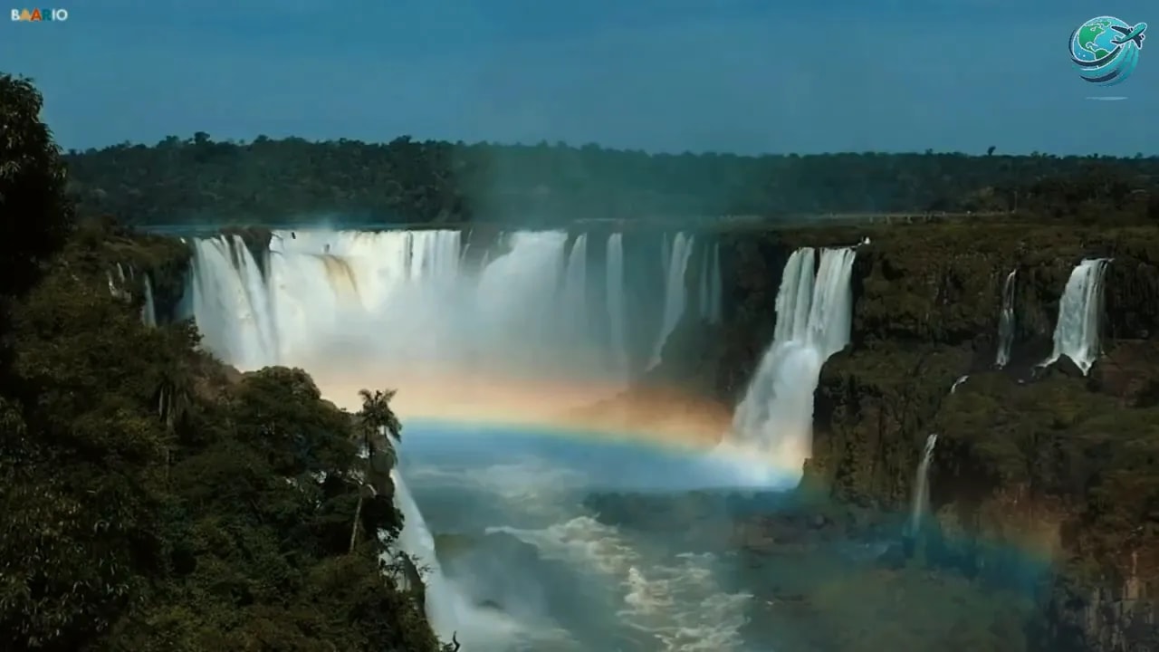 Wide Iguazu waterfalls with a rainbow crossing the misty river