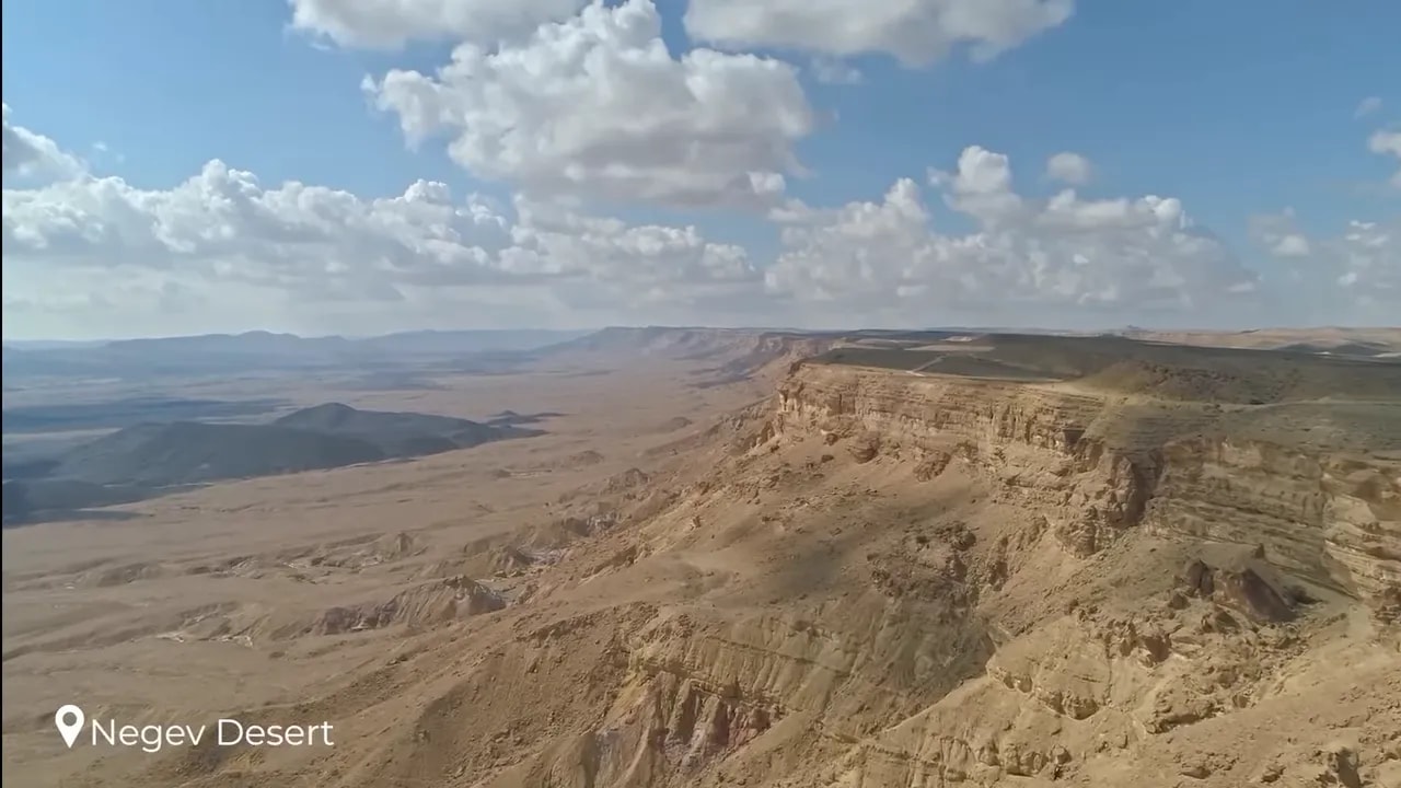 Aerial view of layered cliffs and wide desert terrain at Ramon Crater