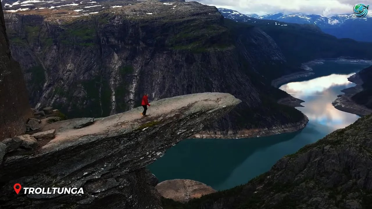 Person standing on Trolltunga rock ledge above fjord