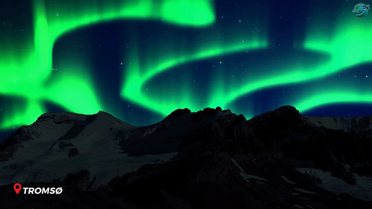 Green northern lights above dark mountain silhouettes
